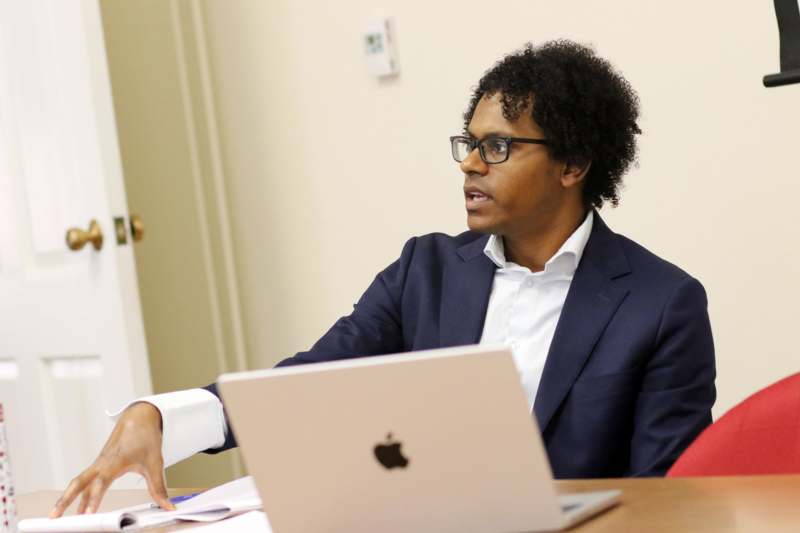 a man in a suit sitting at a desk with a laptop