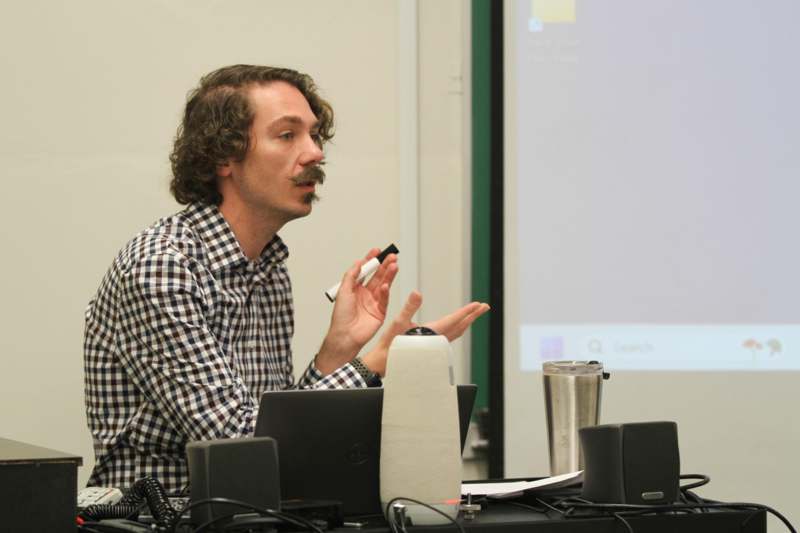 a man with a mustache and a white marker in his hand