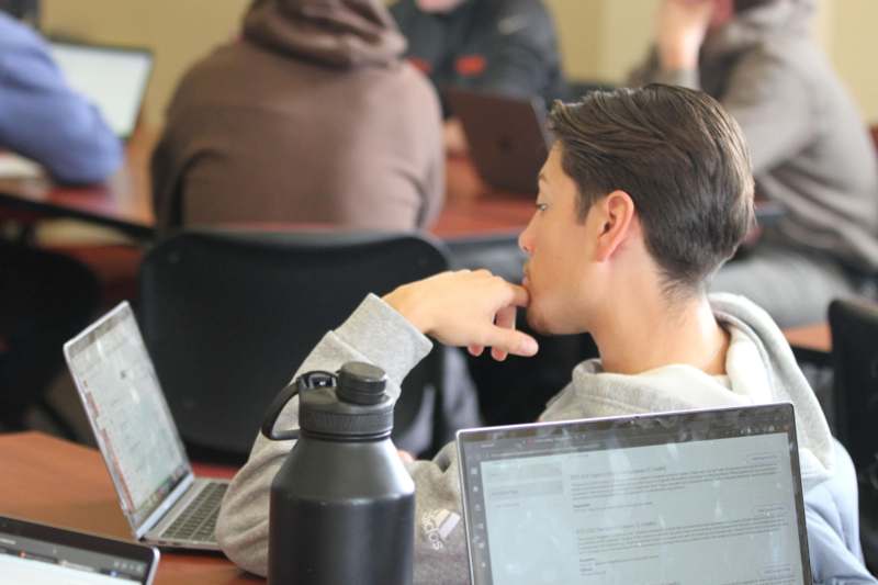 a man sitting at a desk with his hand on his chin