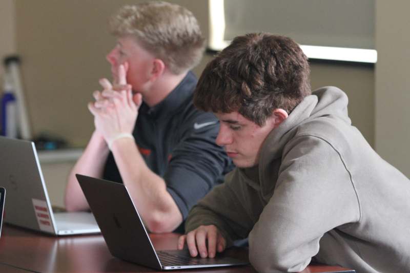 a group of men sitting at a table with laptops
