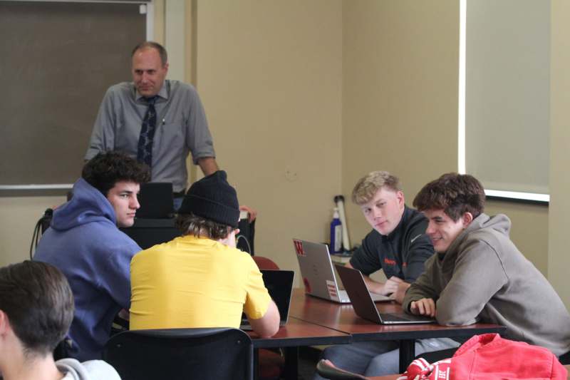 a group of people sitting at a table with laptops