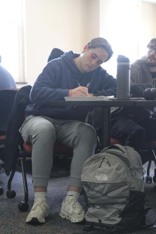 a man sitting at a table writing on a notebook