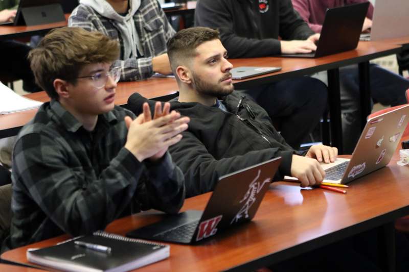 a group of people sitting at tables with laptops