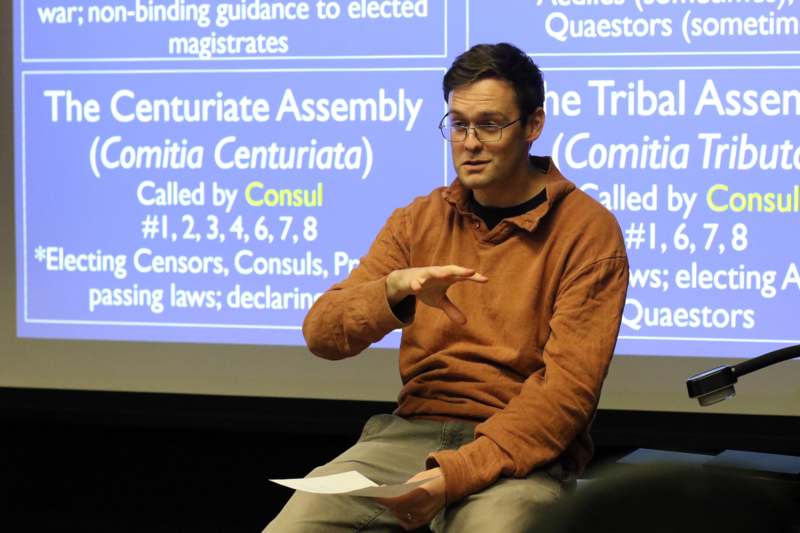 a man sitting in front of a large screen