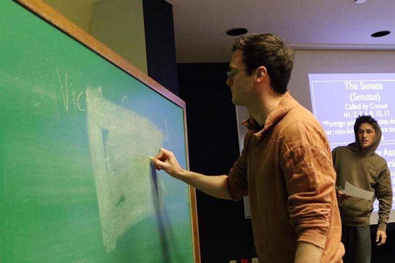 a man writing on a chalkboard