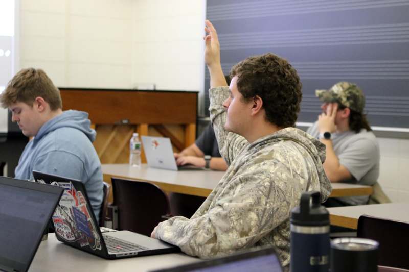 a group of people sitting at tables with laptops