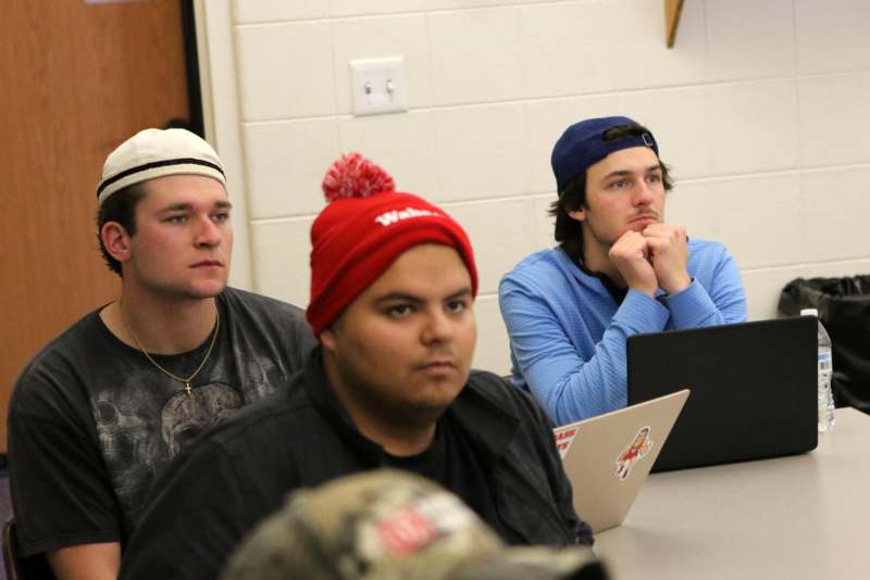a group of men sitting at a table with laptops