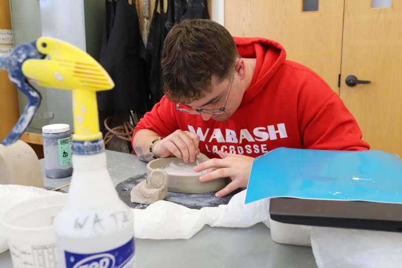 a man in a red sweatshirt painting a bowl