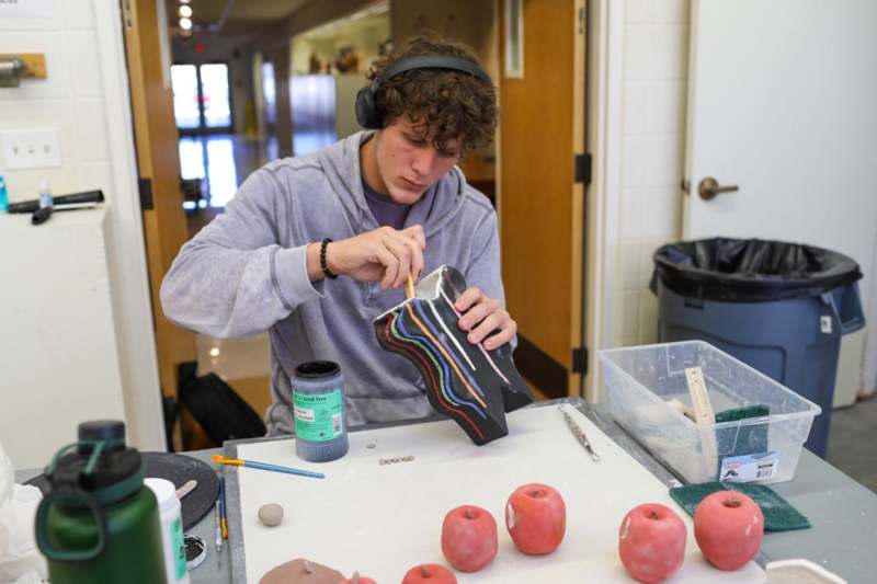 a man wearing headphones painting a sculpture