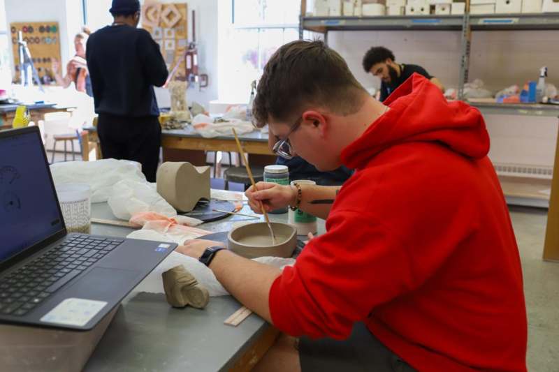 a man painting a bowl with paintbrushes