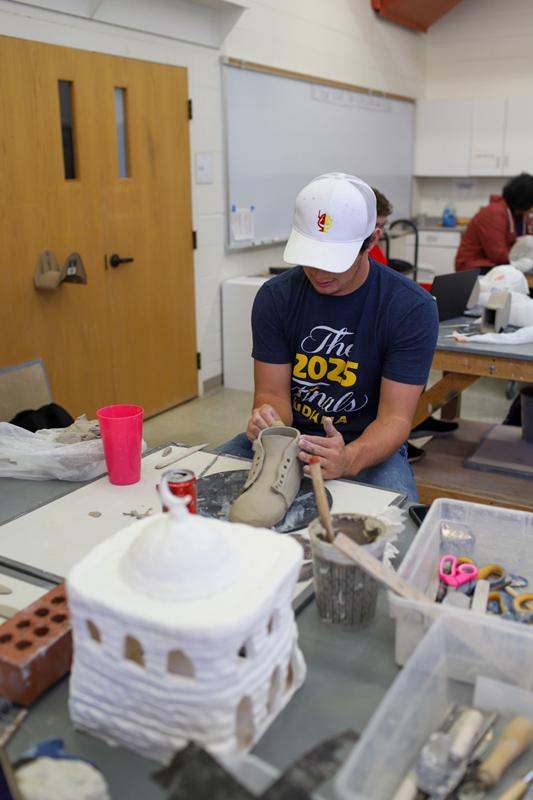 a man in a white hat working on a shoe