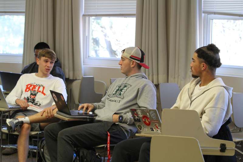 a group of men sitting in chairs with laptops