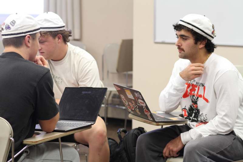 a group of men sitting at desks with laptops