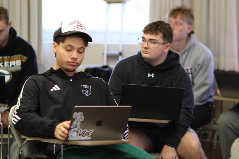 a group of men sitting in a room with laptops