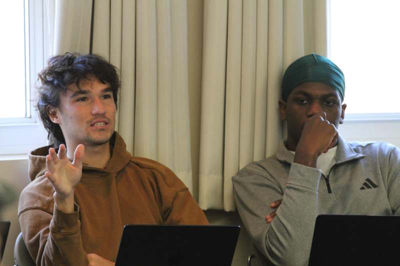 a group of men sitting at a table with laptops