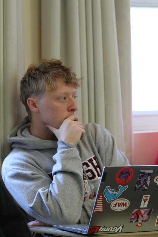 a man holding his chin and looking at a laptop