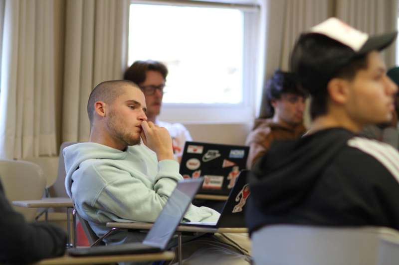 a man sitting in a chair with his hand on his chin