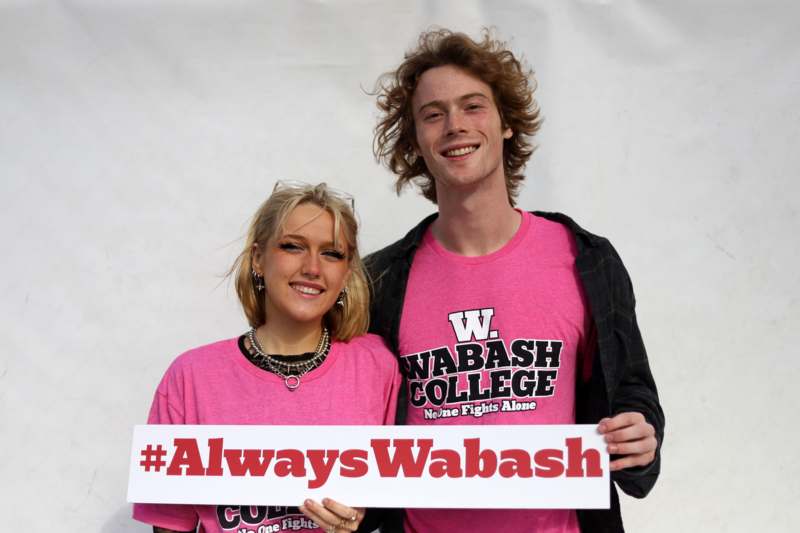 a man and woman in pink shirts holding a sign