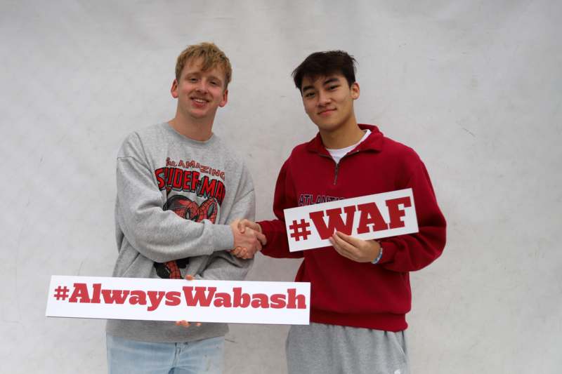 two men shaking hands with a sign
