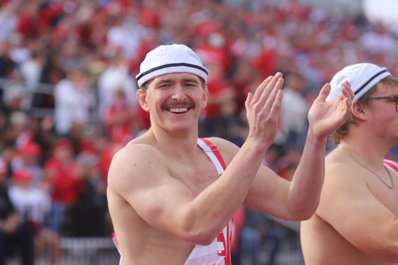 a man wearing a white hat and red vest with his hands up