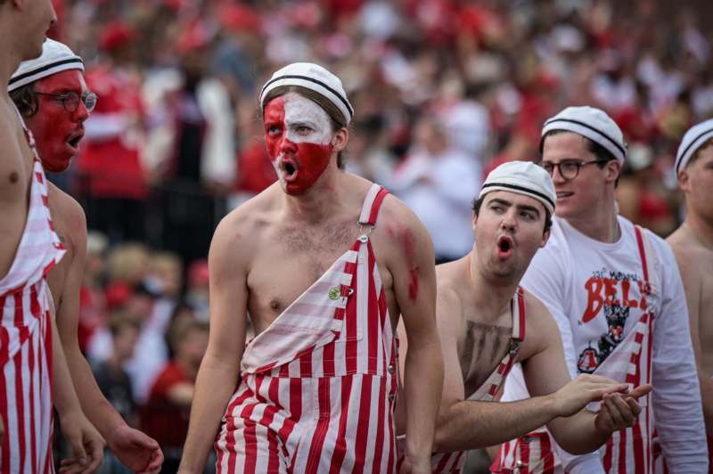a group of men wearing red and white striped overalls and white hats