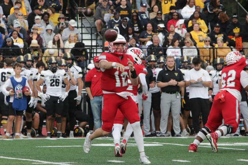 a football player throwing a football in front of a crowd