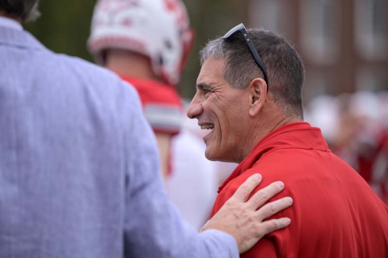 a man laughing with his hand on his shoulder