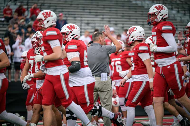 a football team with a coach giving high five