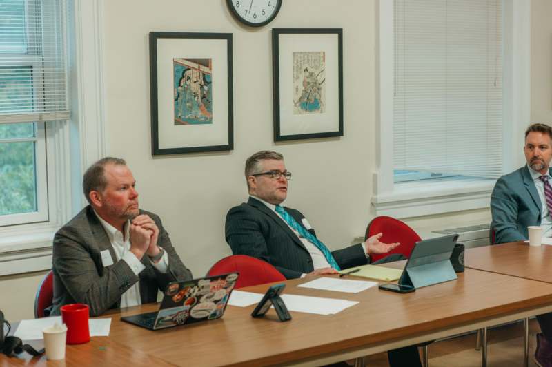 a group of men sitting at a table with laptops