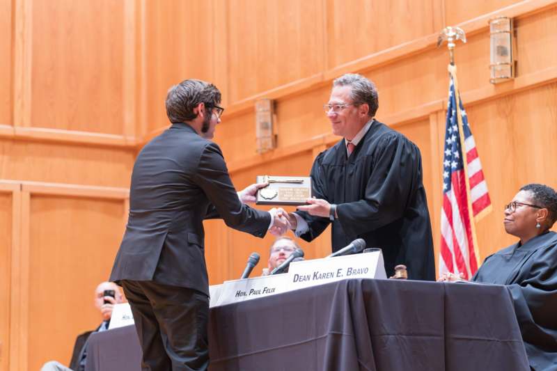 a man in a black robe receiving a plaque from a man in a black robe