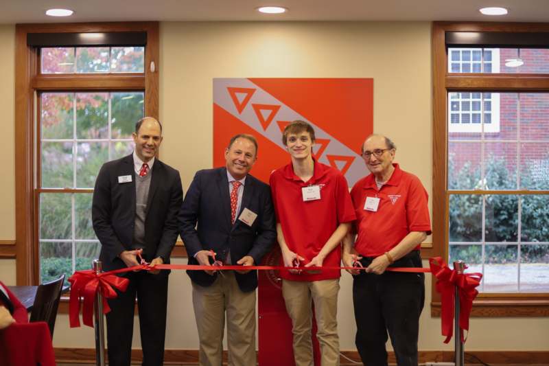 a group of men cutting a red ribbon
