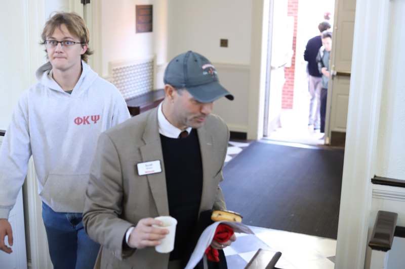 a man in a suit holding a hot dog and a man in a hat