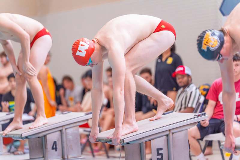 a group of people in swimsuits on diving blocks