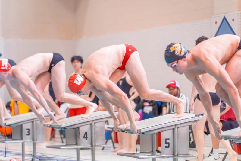a group of people in swimsuits diving into a swimming pool
