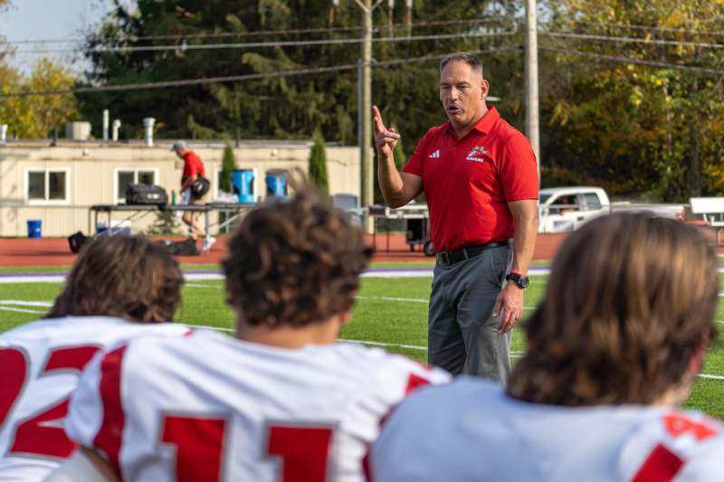 Football at Kenyon (10/18/25) - a man in a red shirt talking to a group of people on a field