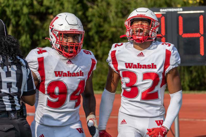 two football players wearing helmets and standing on a field