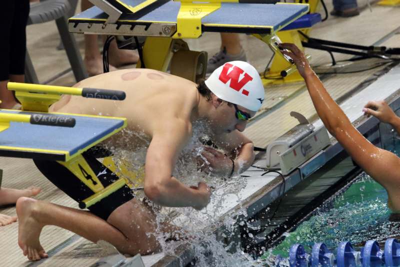 a man in a swim cap jumping into a swimming pool