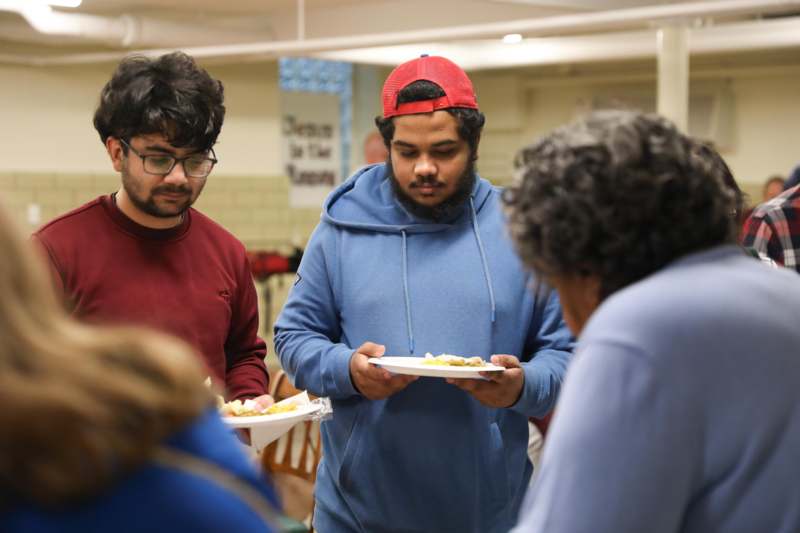 a group of people standing around a table with food