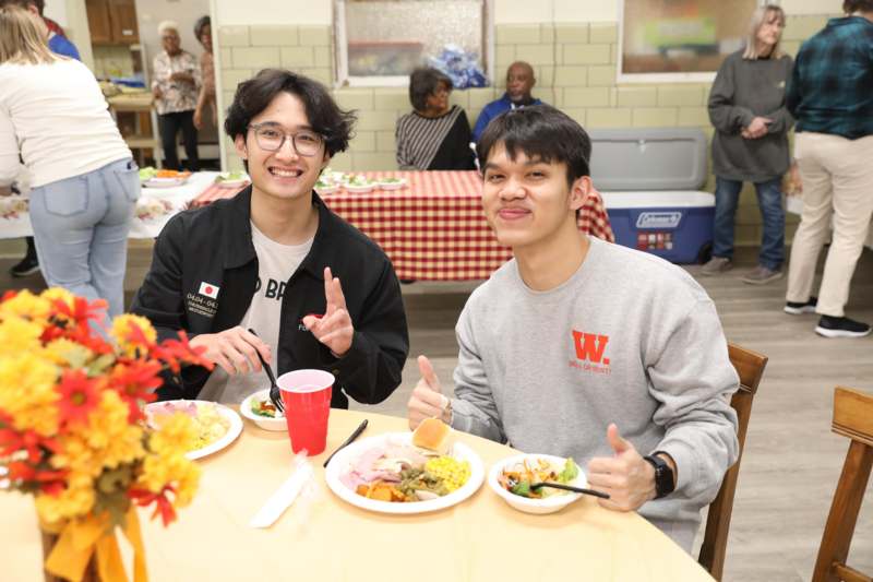 two men sitting at a table with plates of food