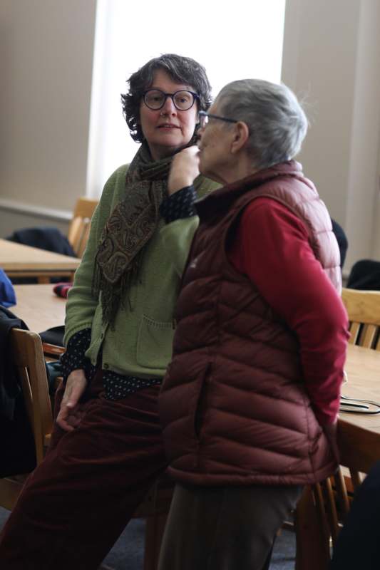 a woman wearing glasses and a scarf standing next to a woman