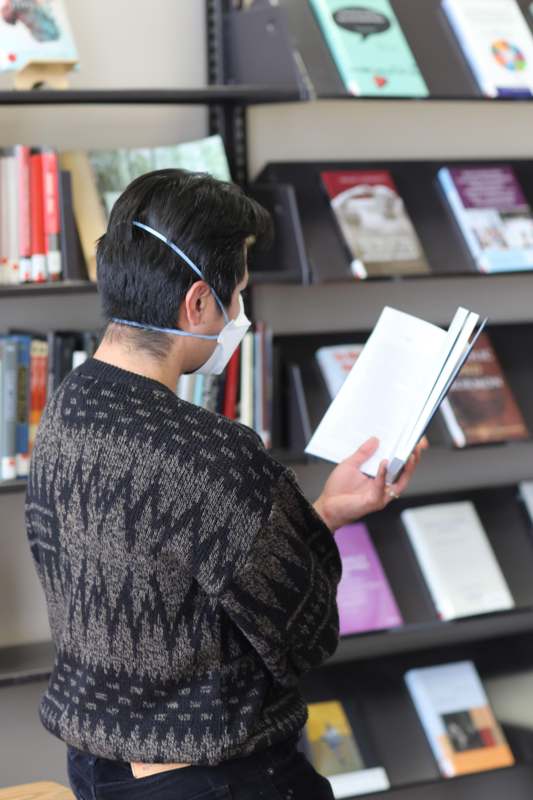 a man wearing a mask reading a book
