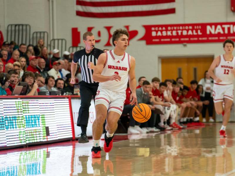 a man running with a basketball in front of a crowd