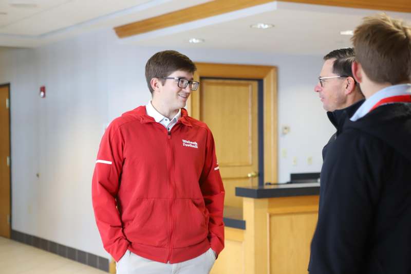 a man in a red jacket talking to a man in a black jacket