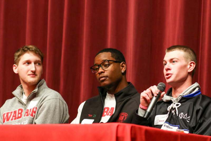 a group of men sitting at a table with a microphone