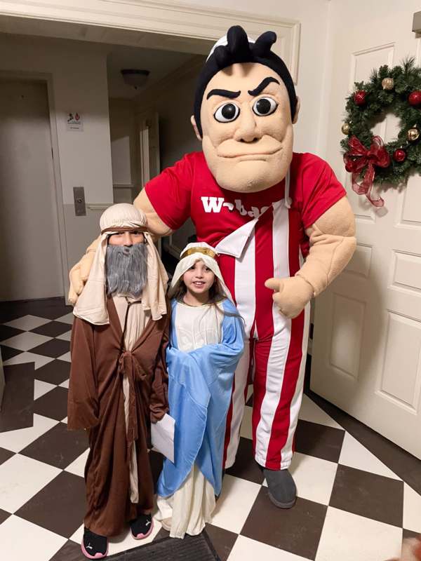 a person in a garment with a child in a room with a wreath