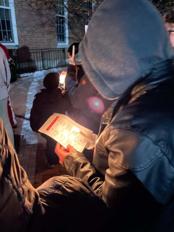 a person holding a paper with a lit candle in front of them