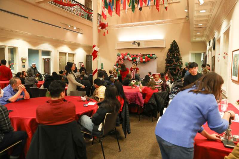 a group of people sitting at tables in a room with a large decorated tree
