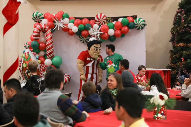 a group of people sitting around a table with balloons and a person in a garment