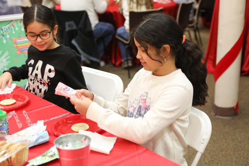 a girl sitting at a table with a red tablecloth and a red tablecloth