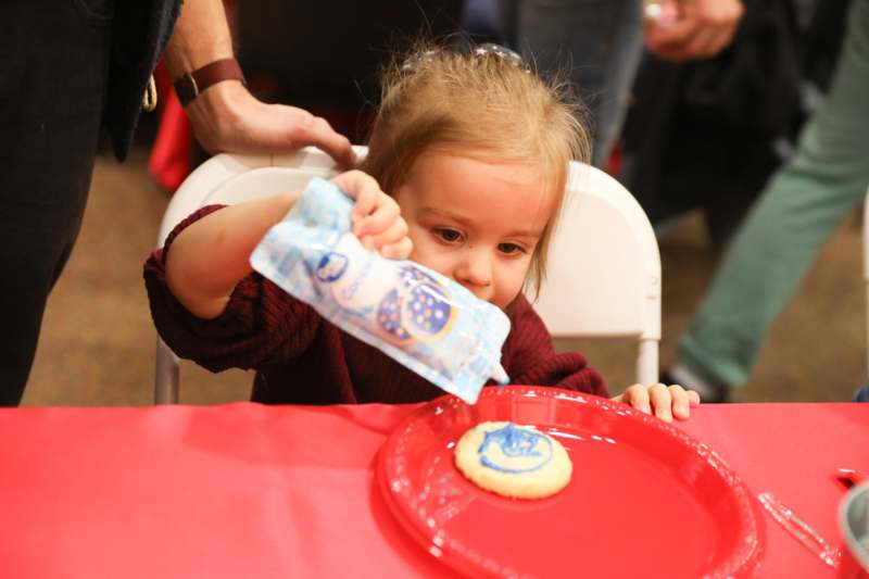 a child sitting in a chair at a table with a red plate and a red tablecloth